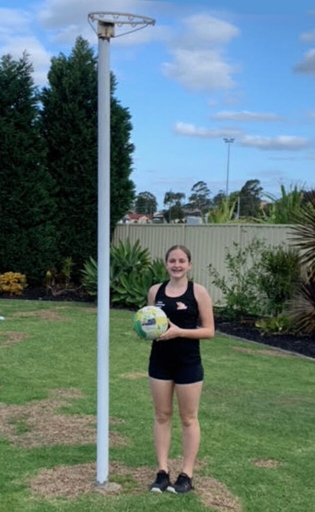jordan-stands with a netball at netball post